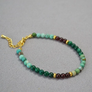 Détail d'un bracelet en perles de malachite, grenat, turquoise avec fermoir doré