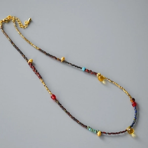 Detail of colorful beaded necklace with yellow teardrop charm and gold extender chain
