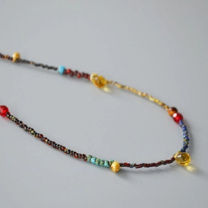 Detail of Miyuki glass beads necklace with deep red spheres and yellow teardrop accents