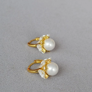Détail des boucles d'oreilles perles en forme de fleur dorées avec des zircons