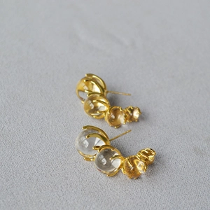 Detail of gold C-shaped earrings with four gradient crystal glass spheres in claw settings