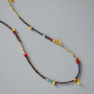 Macro view of boho beaded necklace with yellow teardrop pendants and colorful antique beads
