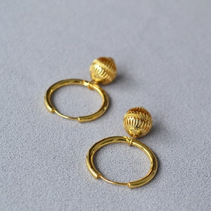 Détail de boucles d'oreilles créoles dorées avec pendentif lanterne ajouré vintage