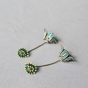Detail of vintage bohemian earrings featuring bronze tulips and turquoise stone inlay