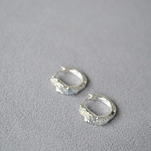 Silver hammered texture hoop earrings with blue crystal accents on grey fabric