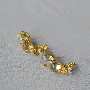 Chic C-shaped gold hoop earrings with gradient glass beads on a grey stone background