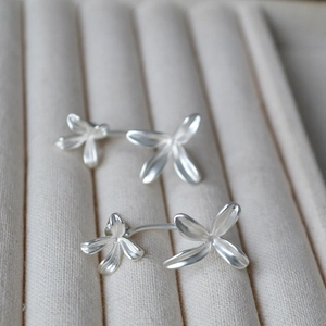 Detailed macro view of matte silver flower earrings on a beige velvet jewelry tray