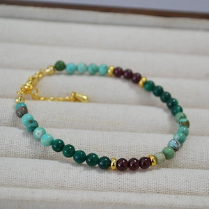 Détail d'un collier en perles de malachite, turquoise et grenat sur un plateau