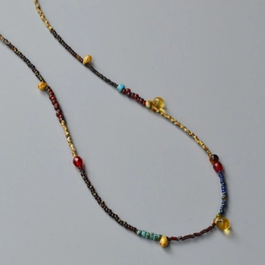 Macro detail of retro beaded necklace with yellow teardrop charms and colorful glass beads