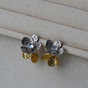 Détail de boucles d'oreilles fleurs martelées bicolores avec un zircon central brillant