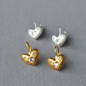 Détail de boucles d'oreilles cœur brossé or et argent avec zircons sertis en étoile