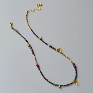 Detail of handmade beaded necklace featuring yellow teardrop charms and gold lobster clasp