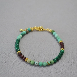 Gros plan détaillé des perles de grenat et malachite avec fermoir mousqueton doré et métal