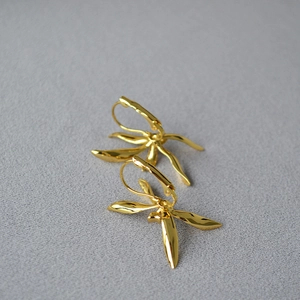 Detailed close-up of gold-plated iris flower earrings with leaf-like curved metal texture