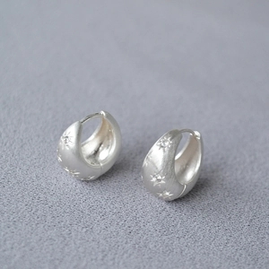 Detailed macro of brushed silver star earrings with micro-inlaid zircon and thick hoop