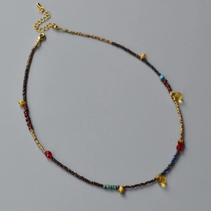 Detail view of colorful bohemian beaded necklace with yellow droplet and gold clasp