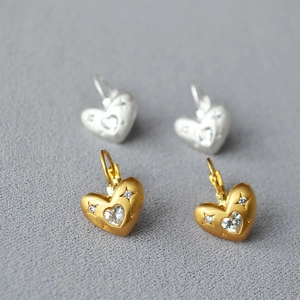 Détail des boucles d'oreilles cœur avec texture mate brossée et accents en zircon étoile