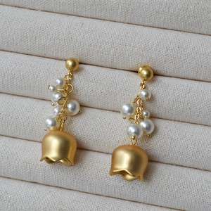 Detailed macro view of vintage lily of the valley earrings with pearls and matte gold finish