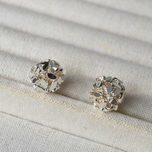 Close-up of geometric faceted hollow silver ball earrings on a jewelry display tray
