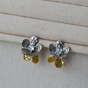 Gros plan de boucles d'oreilles fleur bicolore avec zircon brillant sur tissu beige texturé