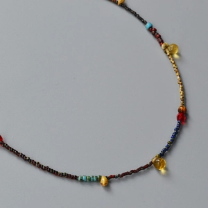 Macro detail of Bohemian beaded necklace with yellow teardrop charms on gray background