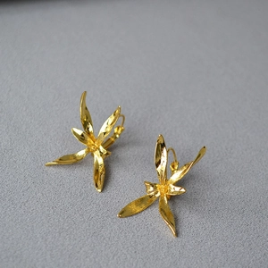 Macro view of gold flower earrings showing detailed metal petals and lily floral texture