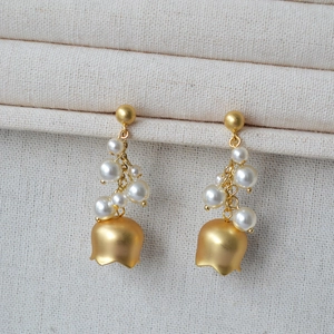 Macro shot of lily of the valley earrings with matte gold floral base and white pearls