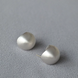 Macro detail of silver bean earrings with fine brushed matte texture and minimalist design