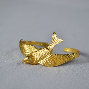 Adjustable gold plated brass cuff bracelet featuring a lifelike flying swallow design