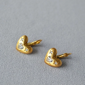 Gros plan détaillé de boucles d'oreilles cœur dorées mates avec zircon et accents d'étoiles