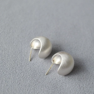 Detailed view of silver hollow hemisphere earrings with minimalist brushed matte finish texture