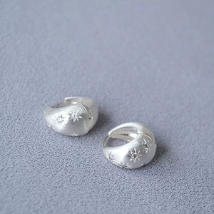 Close-up of matte silver brushed star earrings with inlaid sparkling zircon stones