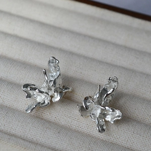 Détail de boucles d'oreilles fleurs argentées sur un plateau à bijoux beige