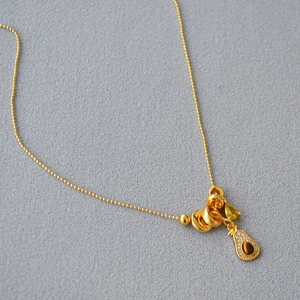 Detail of gold bead chain necklace featuring a teardrop tiger eye pendant with pavé crystals
