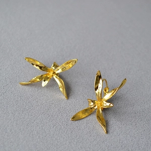 Macro view of gold-plated iris flower earrings with organic textures and metallic luster
