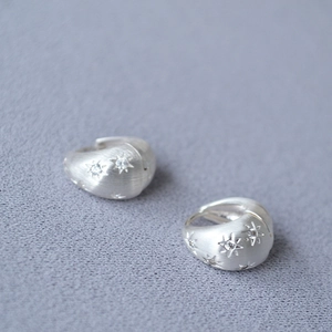 French style silver brushed star earrings with zircon inlay on grey textured background