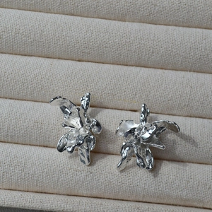 Boucles d'oreilles fleurs 3D irrégulières argentées avec texture organique sur plateau