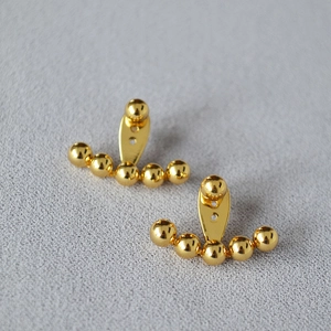 Detalle de pendientes de latón bañado en oro con diseño de cinco cuentas y plata 925