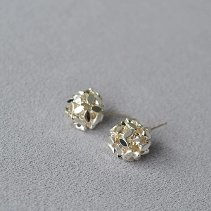 Detailed macro view of faceted hollow ball stud earrings in polished silver finish