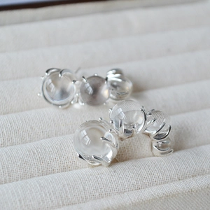 Detailed close-up of C-shaped earrings with transparent glass beads in a jewelry box