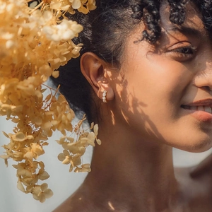 French design gold micro-pave cubic zirconia hoop earrings shown on a female model
