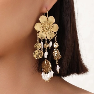 Close-up of golden floral tassel earrings with Baroque pearls and hammered metal discs