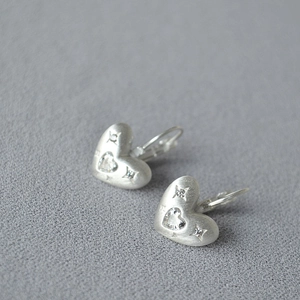 Gros plan de boucles d'oreilles cœur en argent brossé avec un zircon brillant serti en étoile