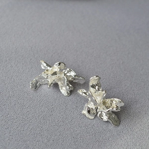 Vue macro des boucles d'oreilles argentées texture lave irrégulière au design floral abstrait
