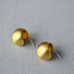 Detailed macro view of gold-plated hollow hemisphere studs with a brushed matte finish