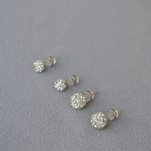 Macro detail of four assorted sizes of sparkling 925 silver pave crystal ball stud earrings