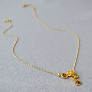 Detail of golden bead chain necklace featuring tiger eye stone and multi-pendant charms