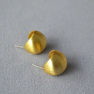 Minimalist brushed gold hollow hemisphere stud earrings on a textured grey background