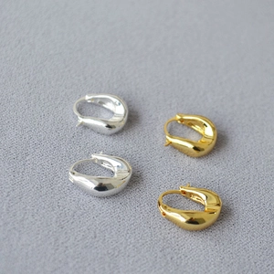 Detail of chunky gold and silver U-shaped earrings with high-polished mirror finish