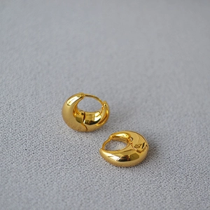 Macro shot of thick high-polished gold-plated brass hoop earrings with a mirror finish
